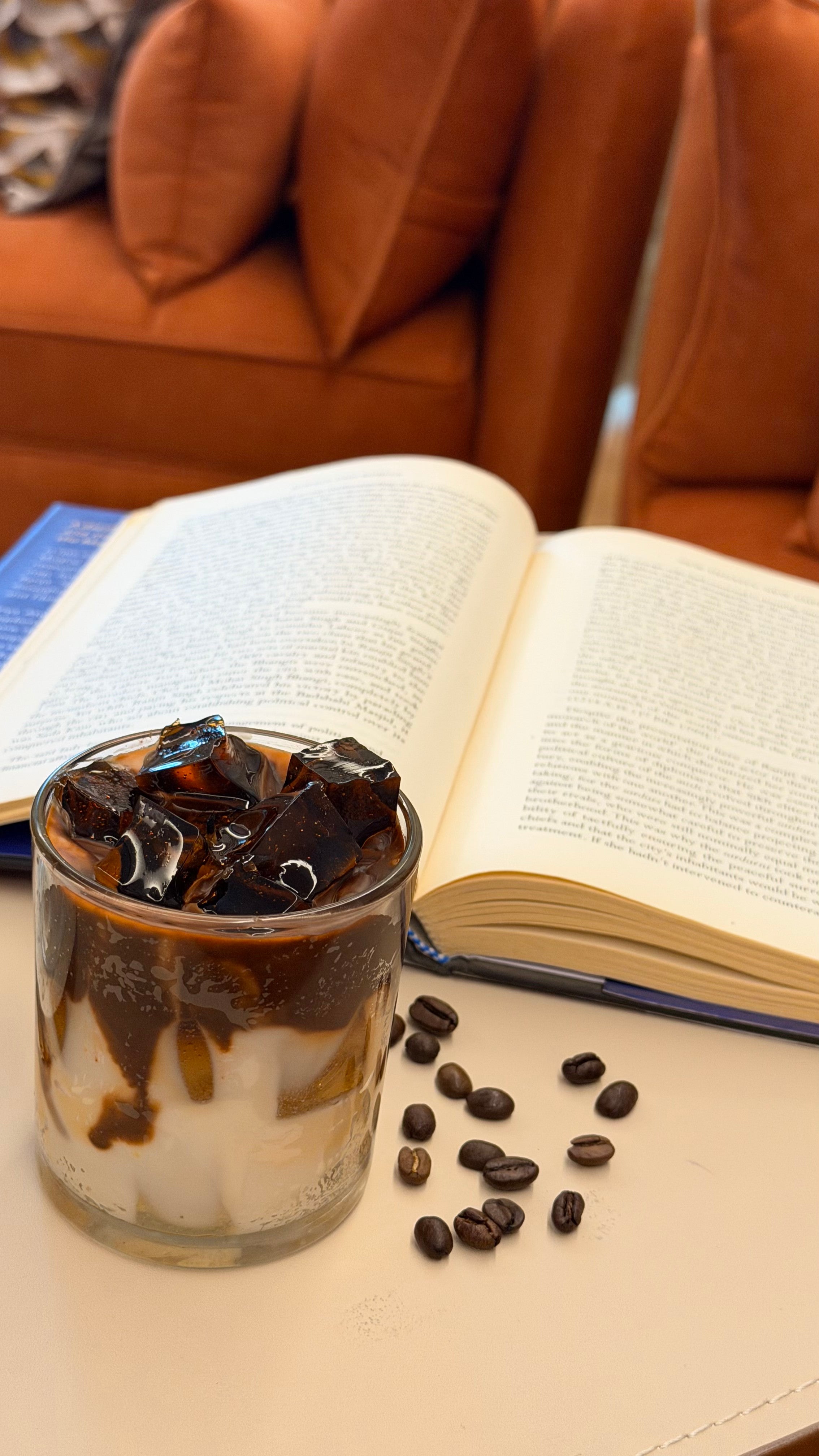 Cold coffee candle styled with an open book and coffee beans